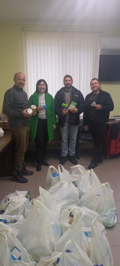 Victor, the mayor, a Peace Corps volunteer, and the mayor's office's social assitant pose with packages of food for the elderly.