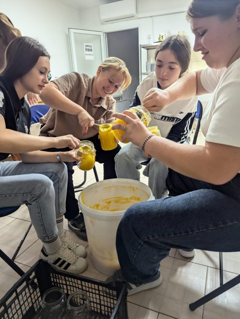 Youth volunteers fill jars with honey.