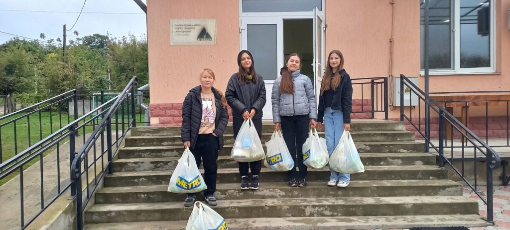 Volunteers pose with packages of food in front of the community center.