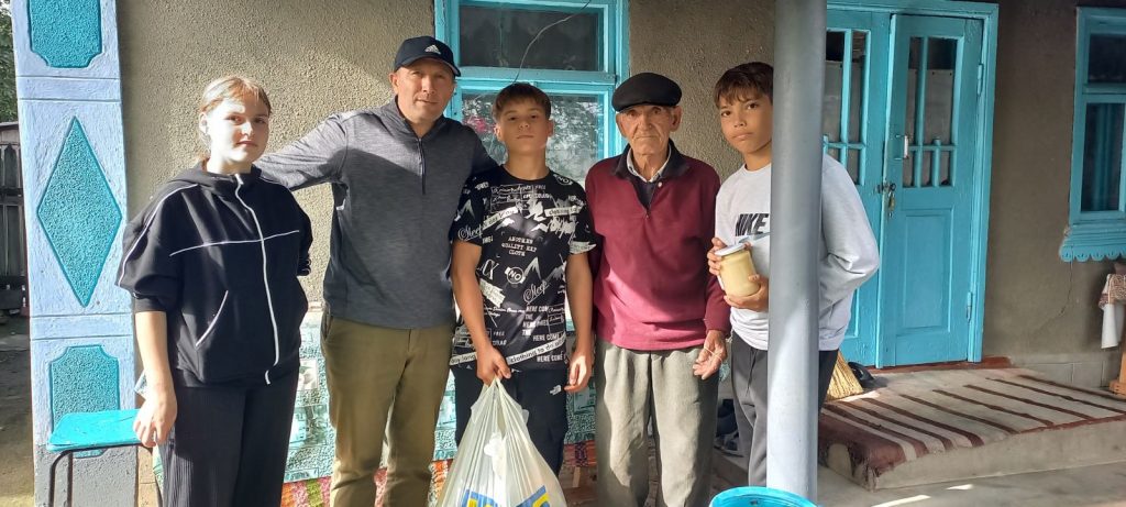 Victor, three volunteers, and a beneficiary of the food package. 