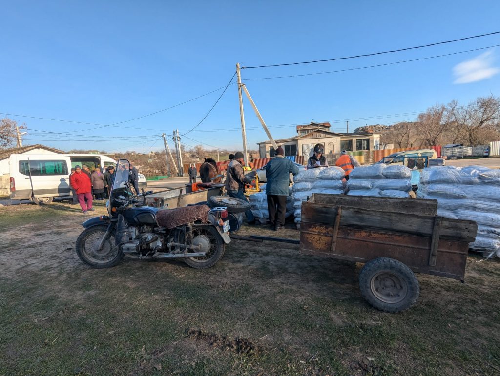 A motorcycle with a cart attached to haul bags of coal.