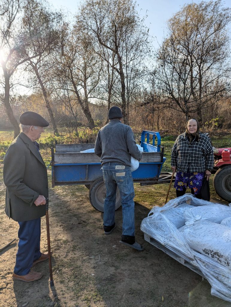 A man loading a trailer with coal for a happy elderly woman.