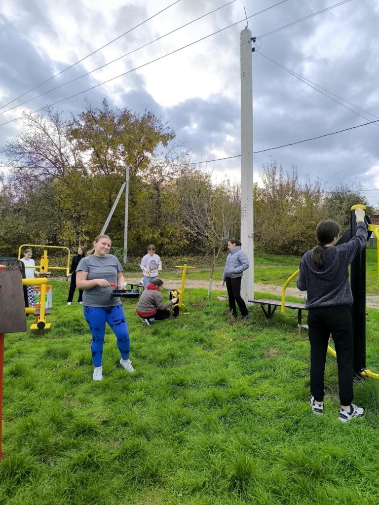 Volunteers painting the outdoor gym equipment