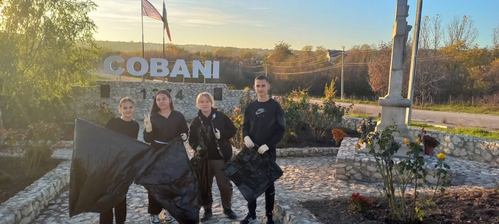 Volunteers posing in front of the Cobani sign with trash bags