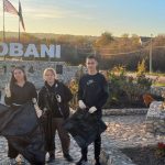 Volunteers posing with trash bags in front of the Cobani sign