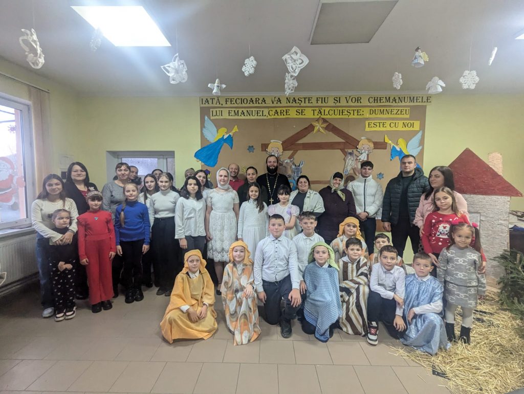 Children posing with their parents, the priest, the teacher and Victor Zama.