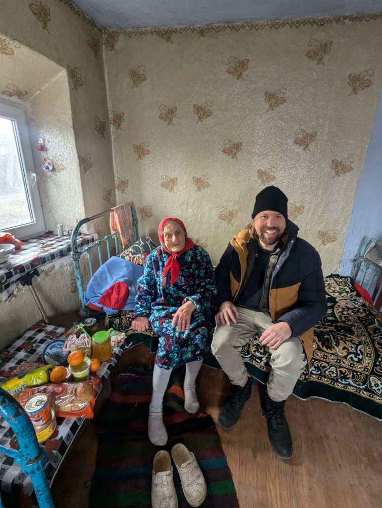 Peace Corps Volunteer Adam with an elderly beneficiary.