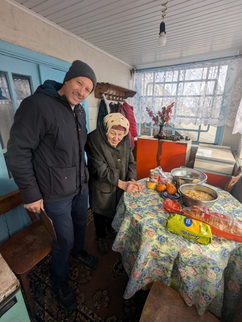 Victor and elderly beneficiary posing with the food delivery.