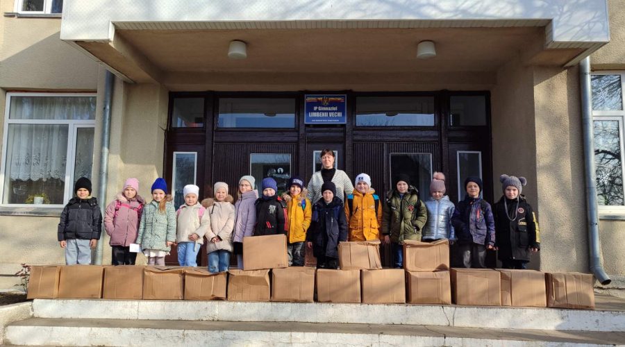 Children with their gifts in front of a school.