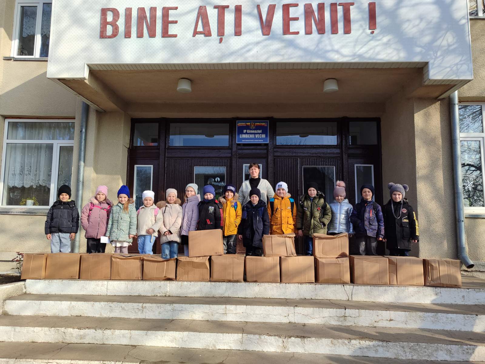 Children with their gifts in front of a school.