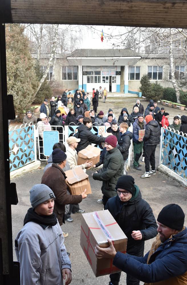 Teenagers unloading gifts and passing them to parents at a school.