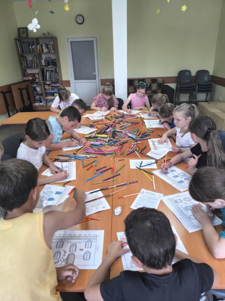 Many kids at the summer camp coloring pictures.