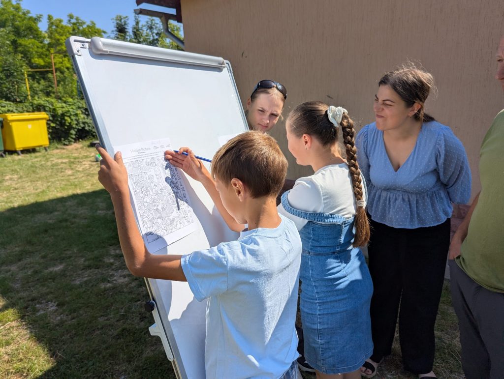 Two kids in front a whieboard, searching for hidden objects in a picture.