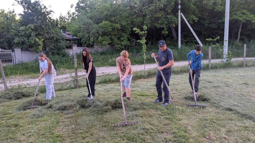 Mr. Victor and four volunteers raking cut grass.