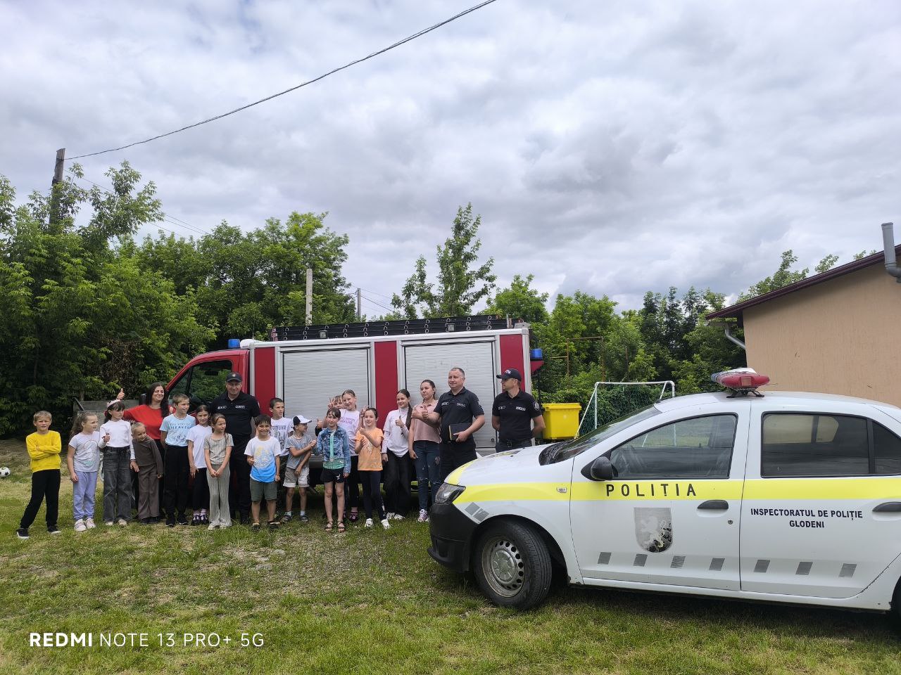 The children posing in front of the fire engine and the police car with the firemen and Mrs. Angela.