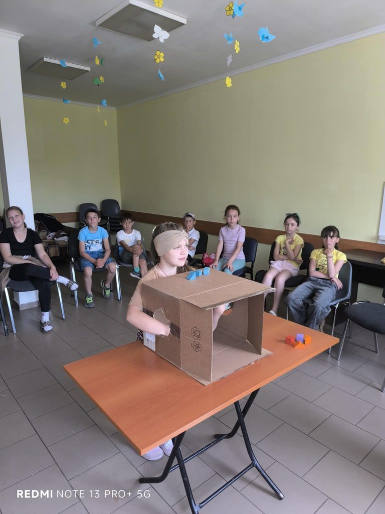 A girl at the kid's game playing a game with a secret item in a box.