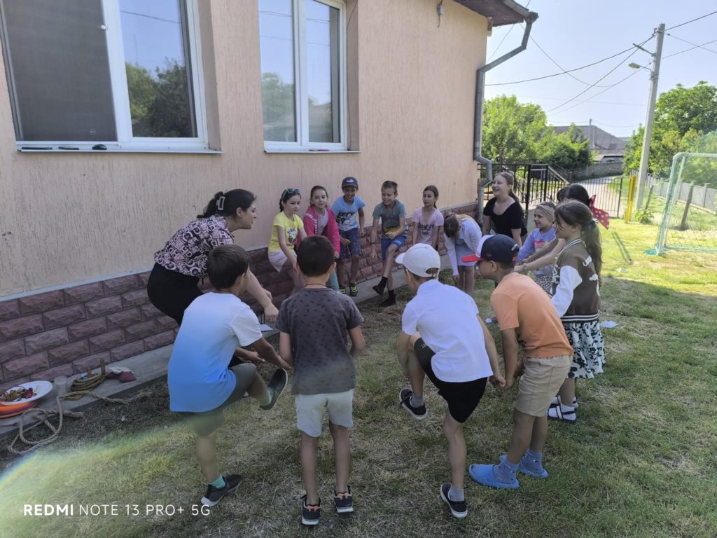 The kids outside with Mrs. Angela standing in a circle and touching their toes.