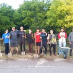 Eight youth olunteers with Victor and the Peace Corps Volunteer Adam, posing with their shovels after spreading dirt in the park.