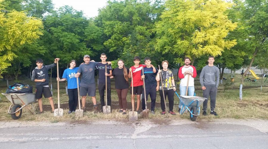 Eight youth olunteers with Victor and the Peace Corps Volunteer Adam, posing with their shovels after spreading dirt in the park.