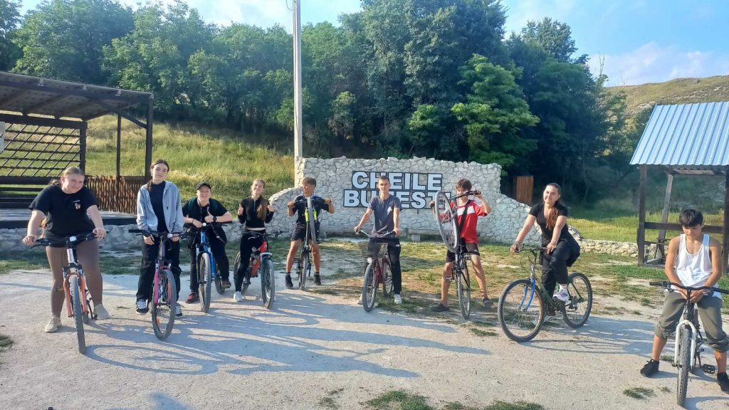 Nine volunteers on their bikes in front of the "Cheile Butesti" sign.