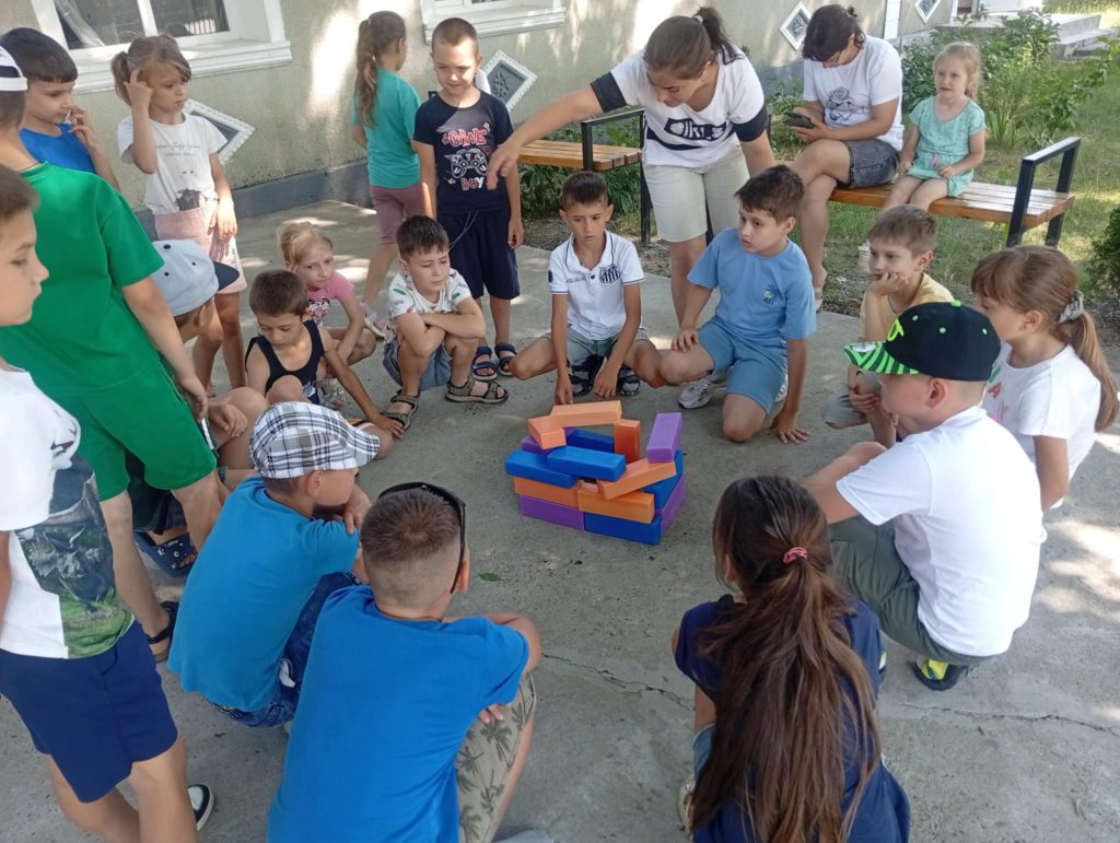 Kids building something with blocks while Angela gives instructions