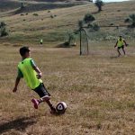 A boy kicking a soccer ball toward the goal