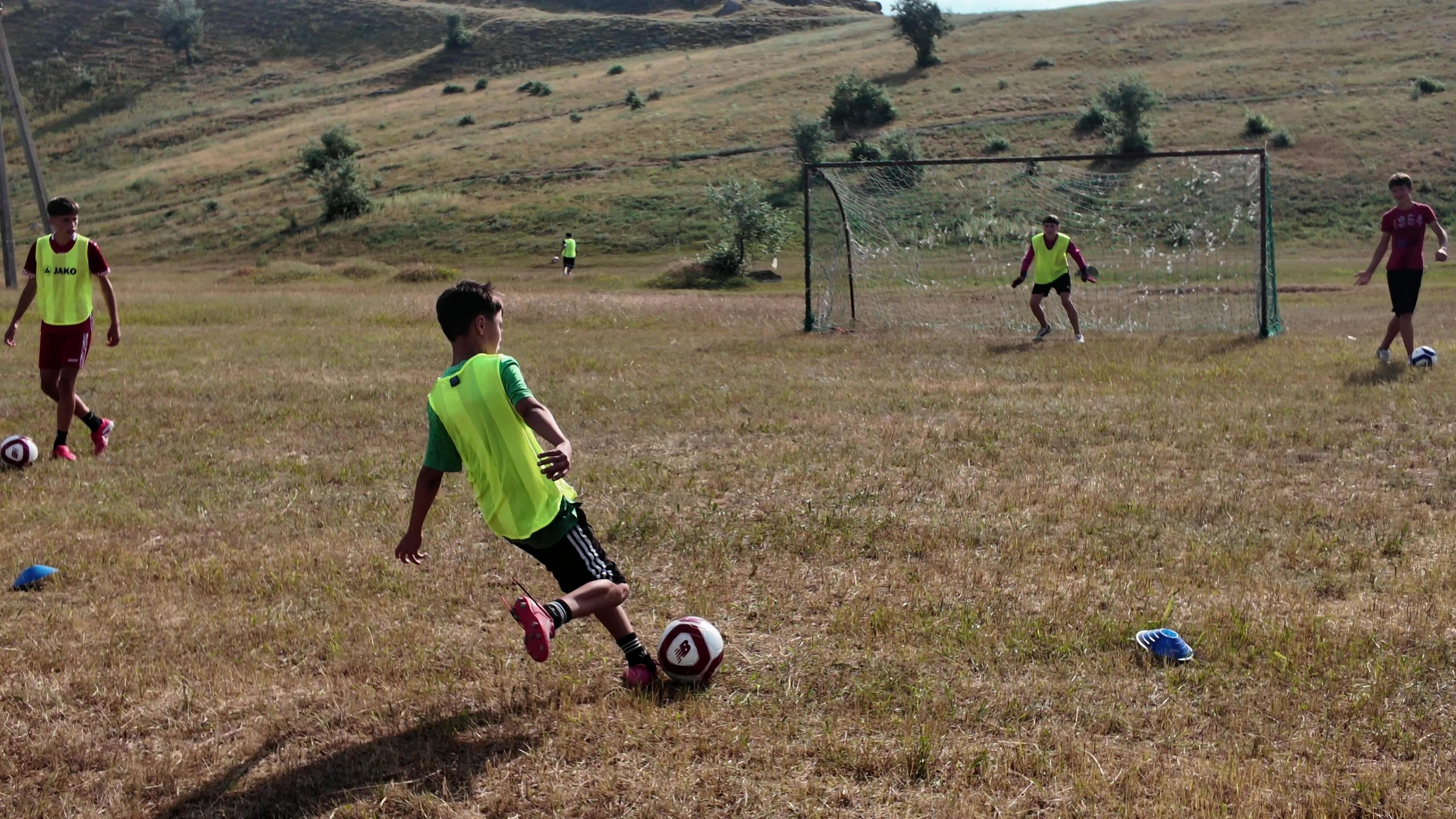 A boy kicking a soccer ball toward the goal